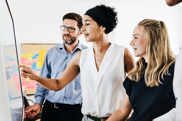 Three people collaborating and interacting with a screen.