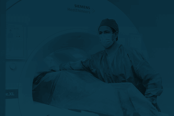 A technician assisting a patient lying down on a stretcher in an MRI machine.