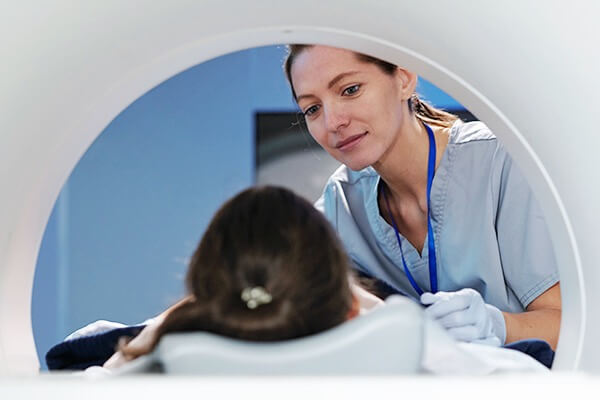 A healthcare professional checking on a patient in an MRI machine.