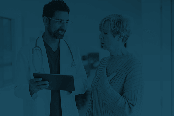 A doctor showing test results to a patient on a tablet.