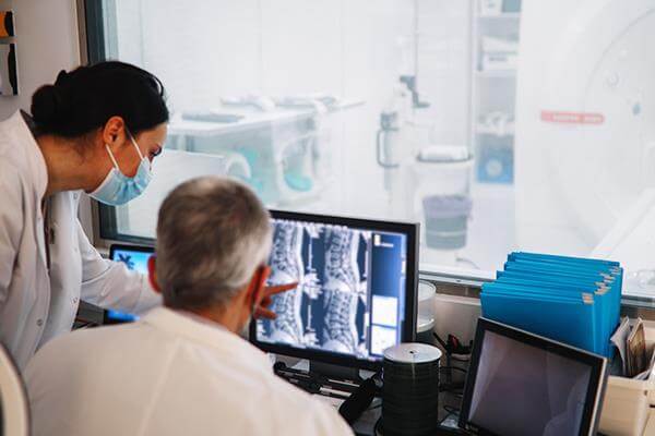 Two doctors reviewing scan results on a computer monitor.