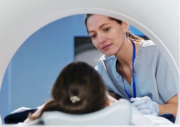 A healthcare professional checking on a patient in an MRI machine.